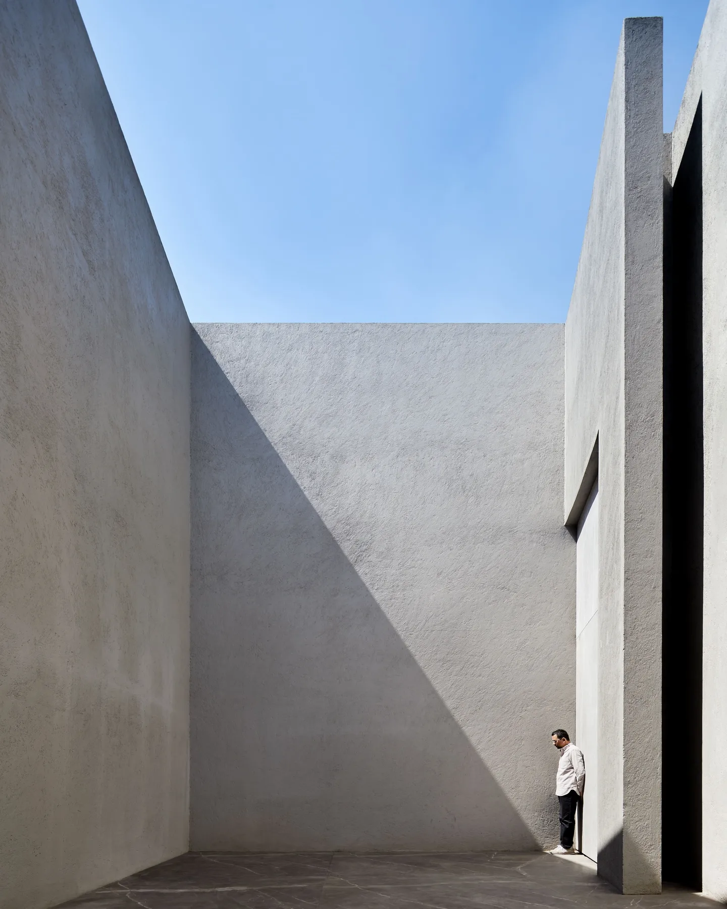 Casa CN: dos muros de concreto de gran altura; una persona al pie da la escala