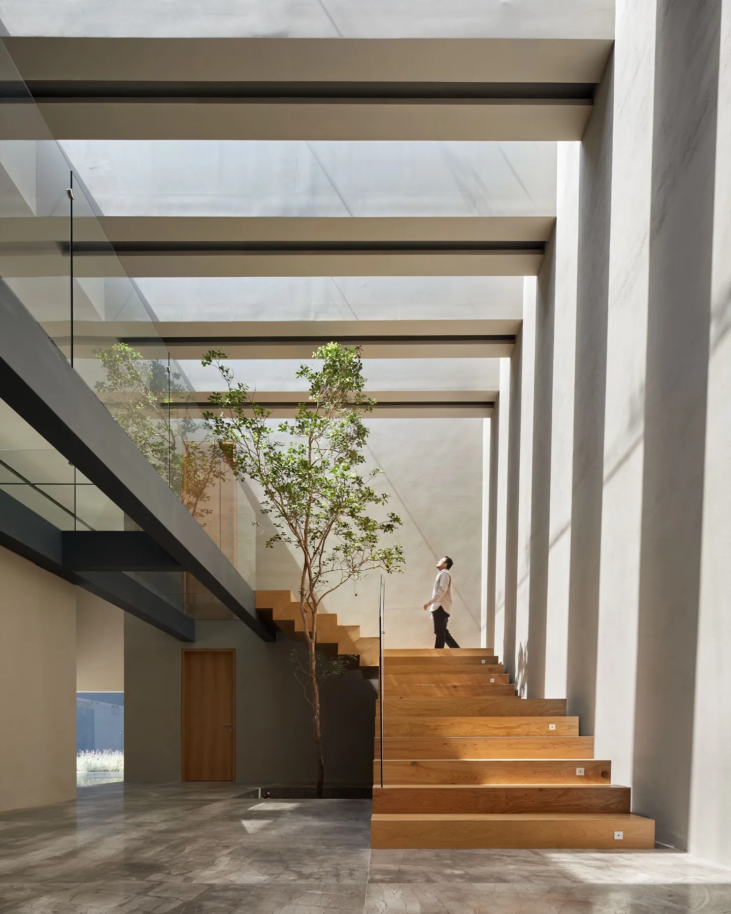 Casa CN: escalera de madera en el atrio bajo el tragaluz