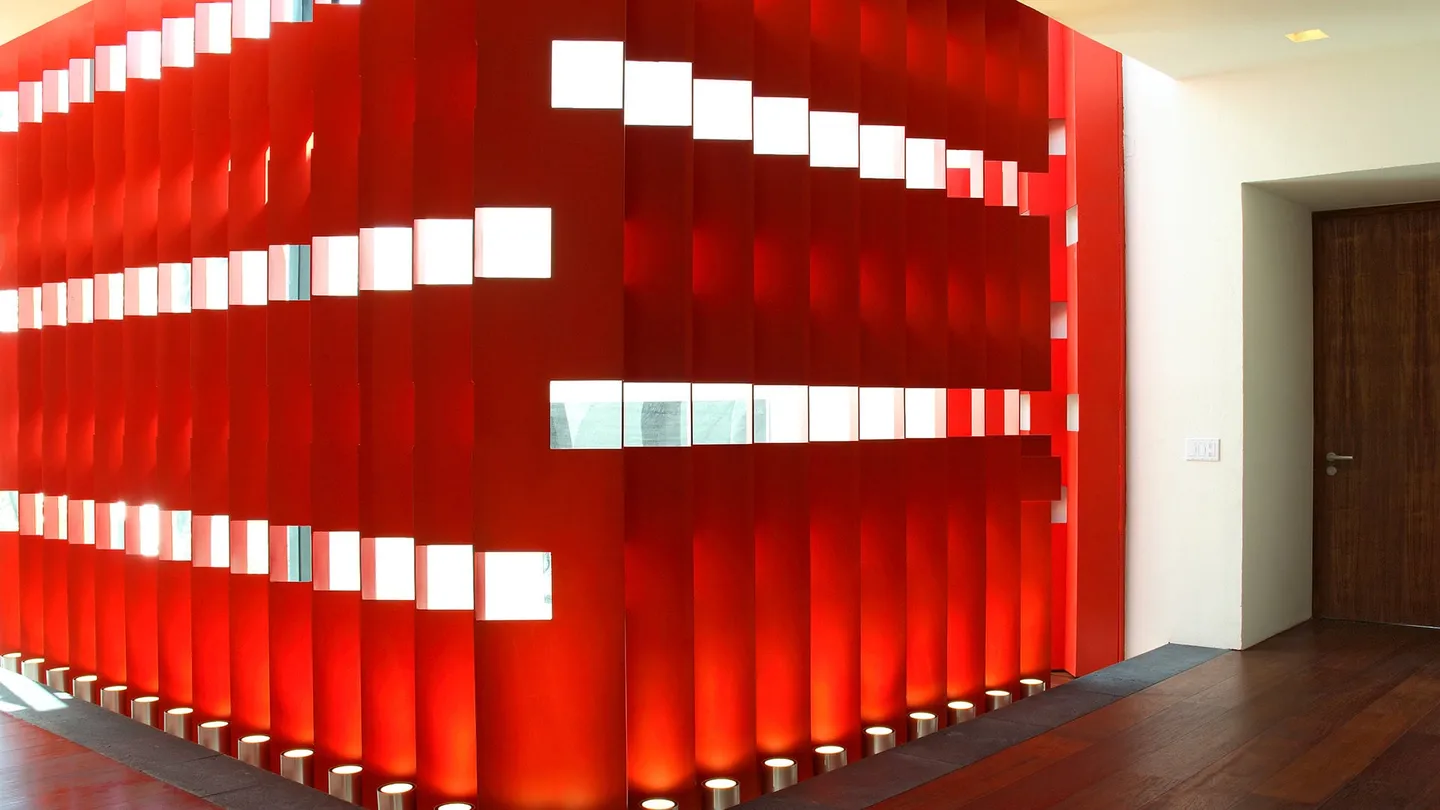 Casa F1: celosía roja de lamas verticales iluminada desde el piso
