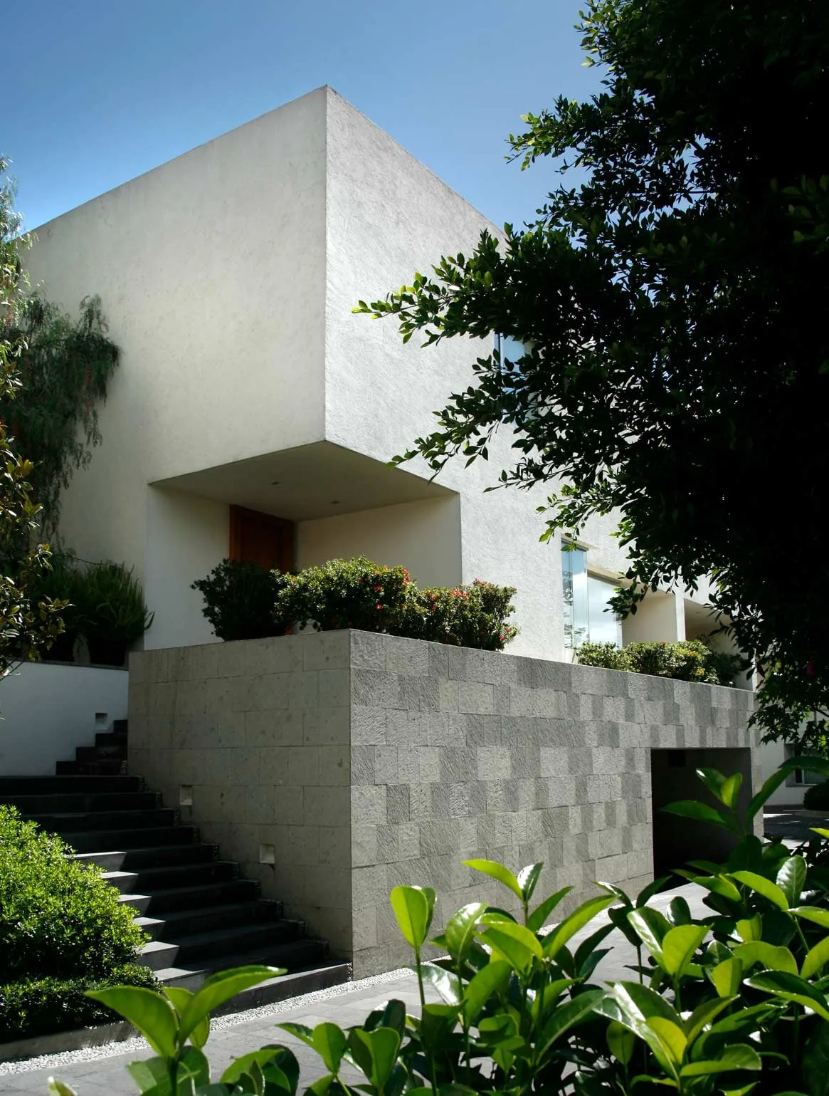 Conjunto AG: volúmenes blancos escalonados sobre un muro de piedra