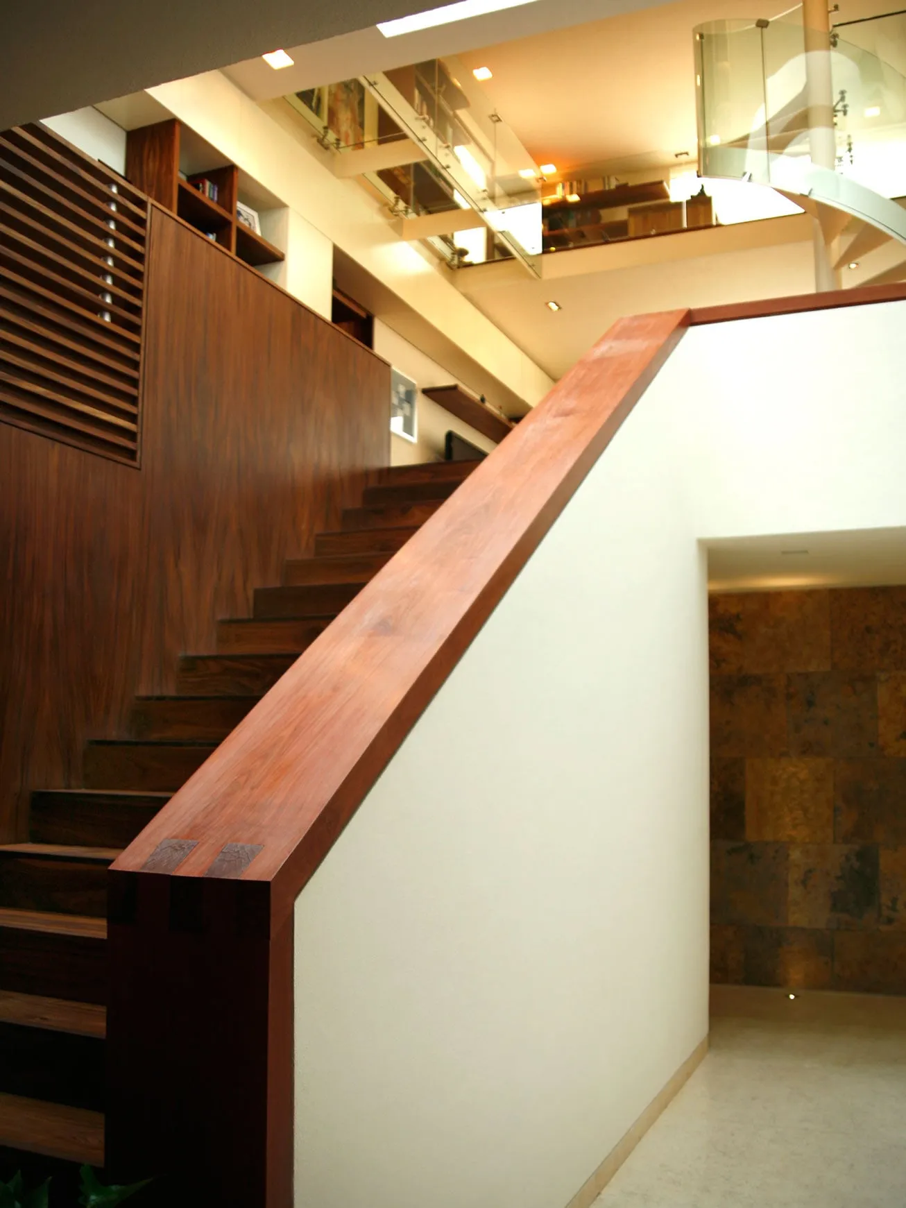 Casa FU: escalera con barandal de madera junto a un muro de lamas