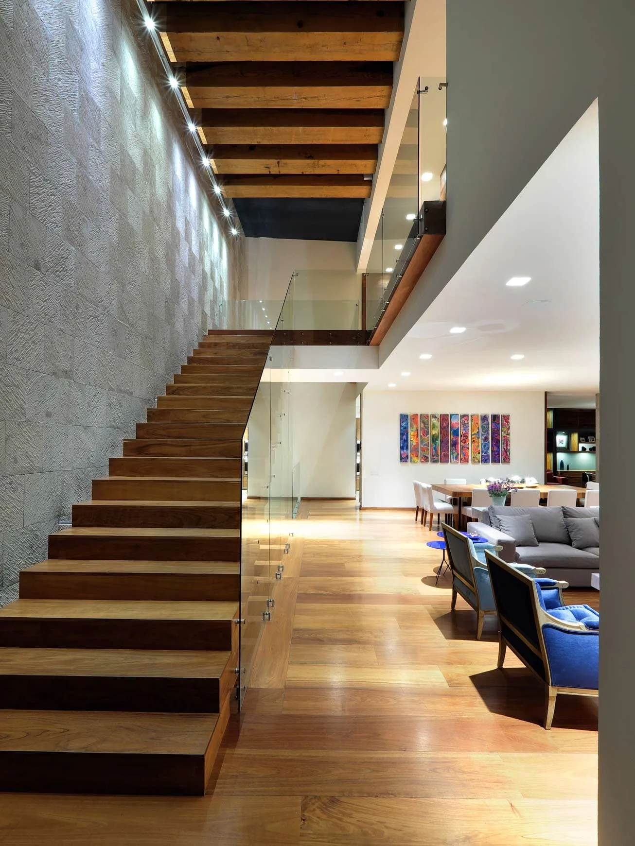 Casa FA: escalera de madera suspendida junto a un muro de piedra