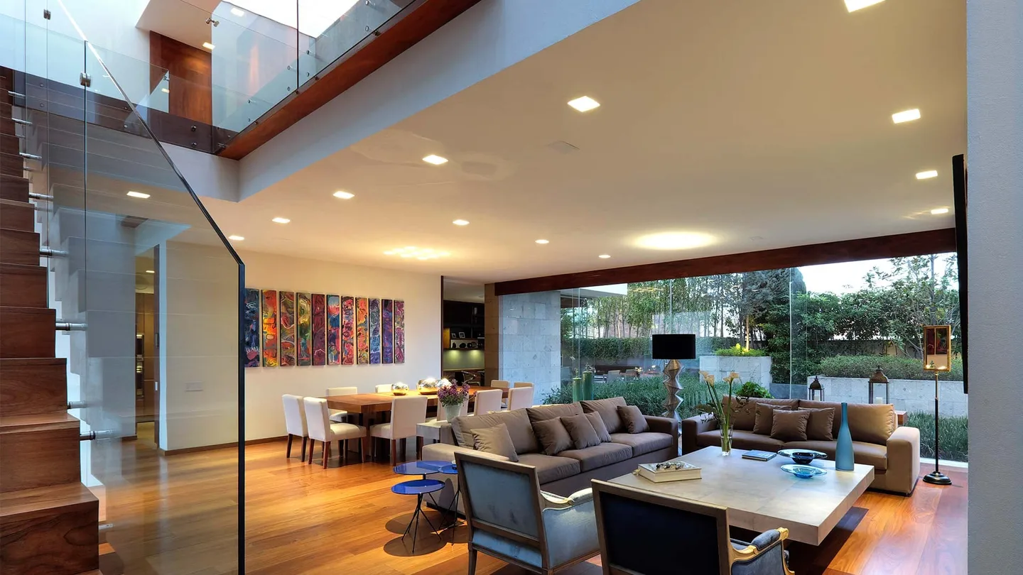 Casa FA: estancia y comedor abiertos al jardín bajo la doble altura