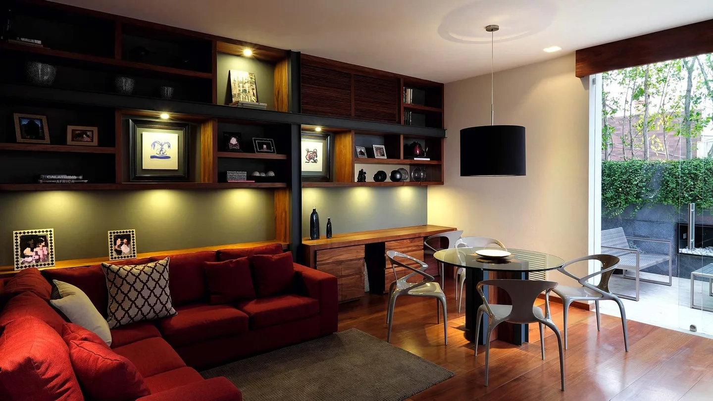 Casa FA: salón familiar con libreros de madera y sofá rojo