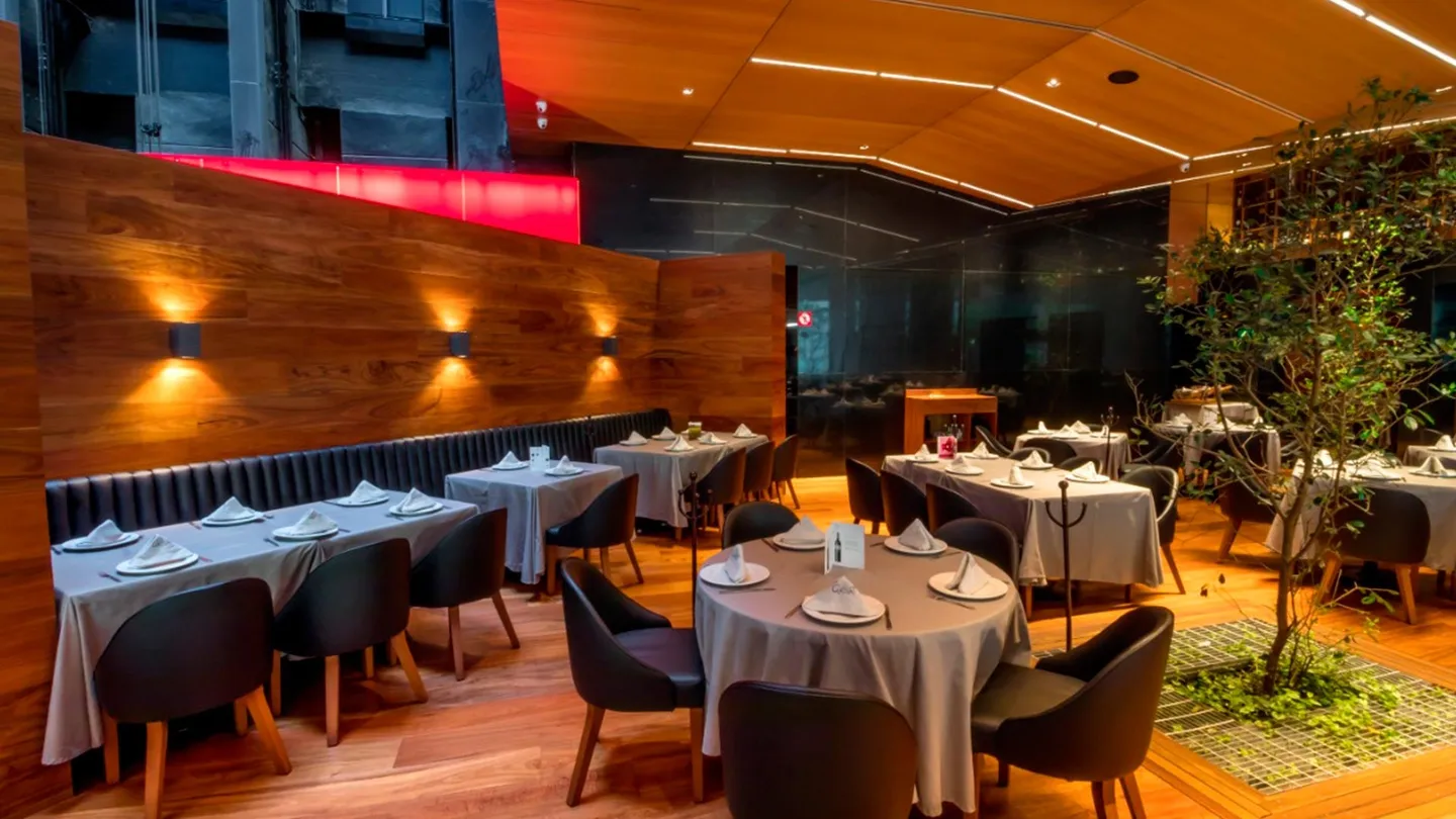 Centro Asturiano Polanco: mesas junto a un muro de madera con apliques de luz