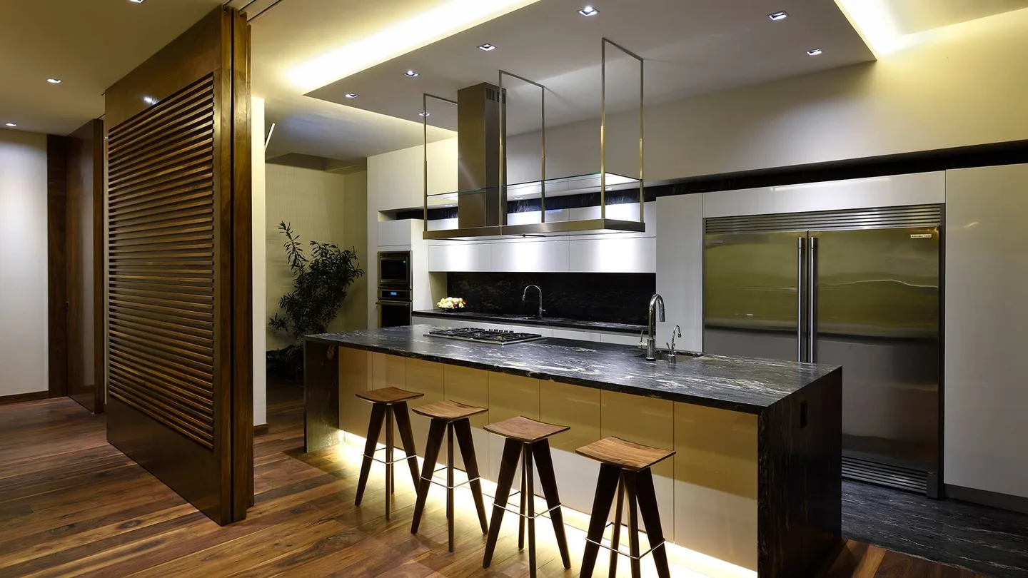Casa CR: cocina con barra iluminada y panel de lamas de madera