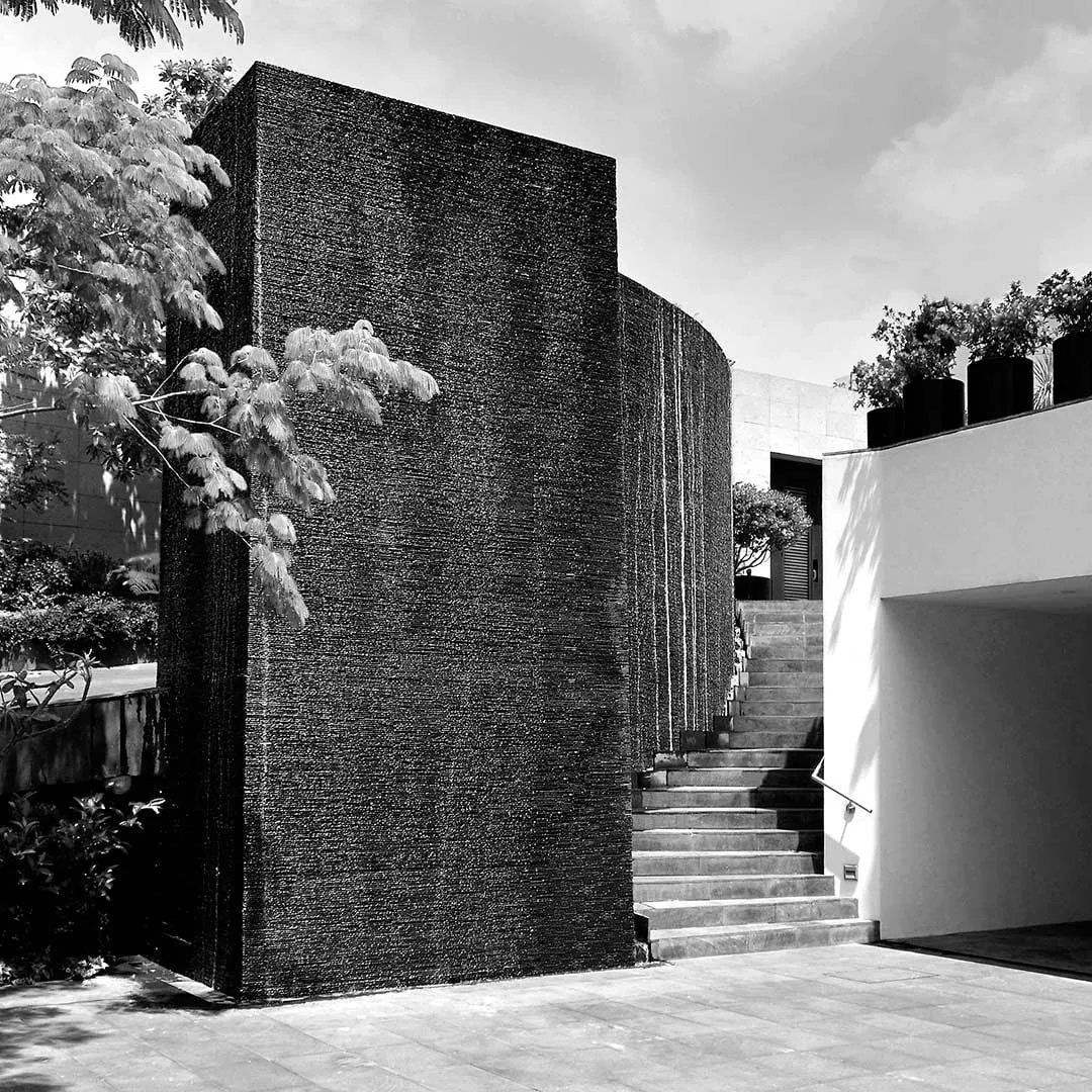 Casa CR: muro de piedra oscura y escalera exterior, en blanco y negro