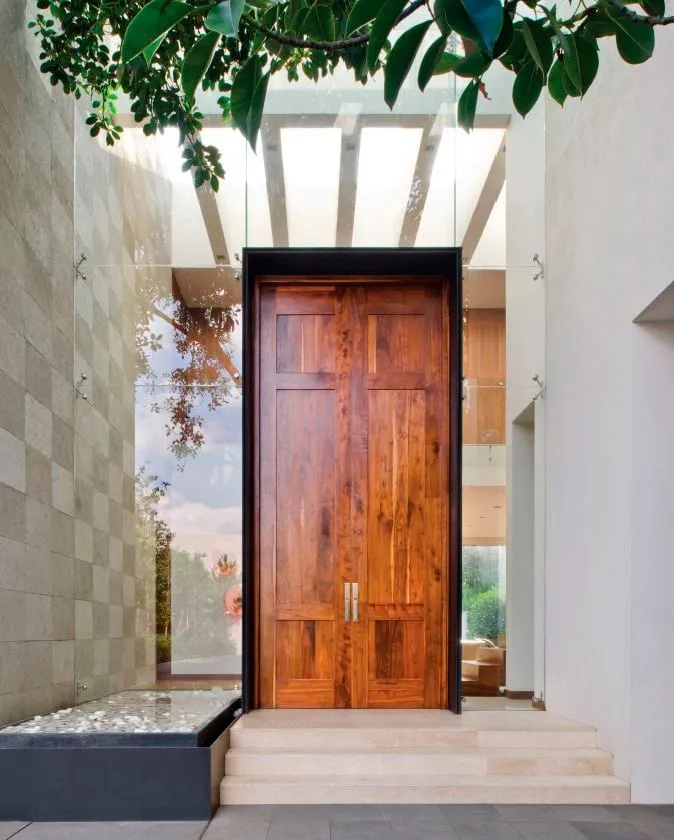 Casa RI: puerta de madera en el acceso entre muros de piedra