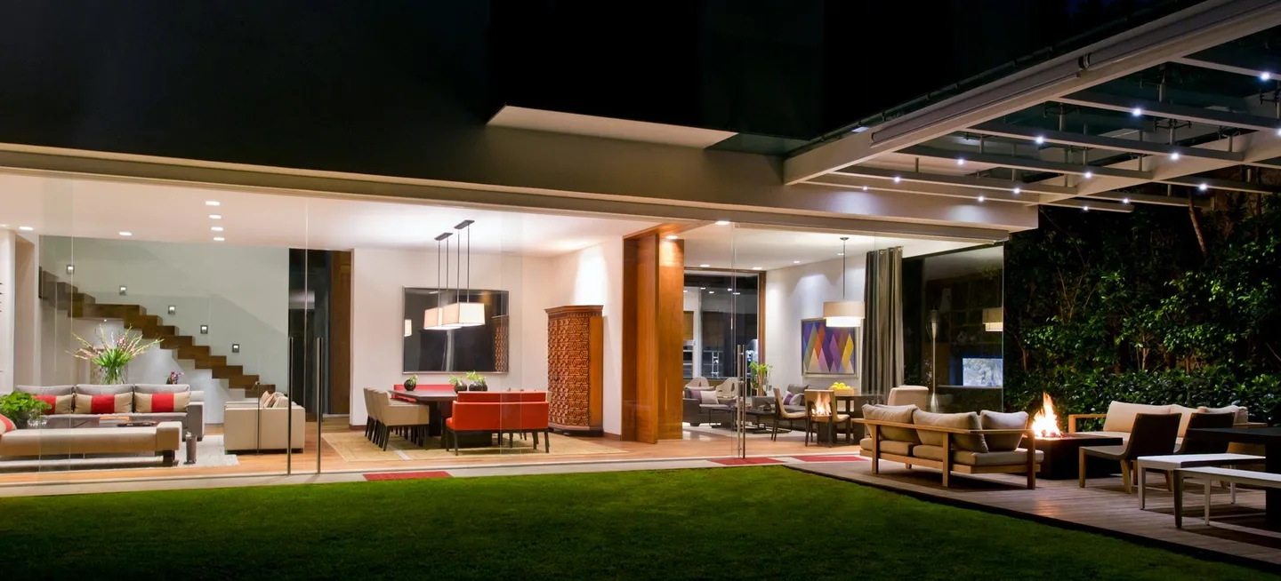 Casa RI: fachada al jardín iluminada de noche