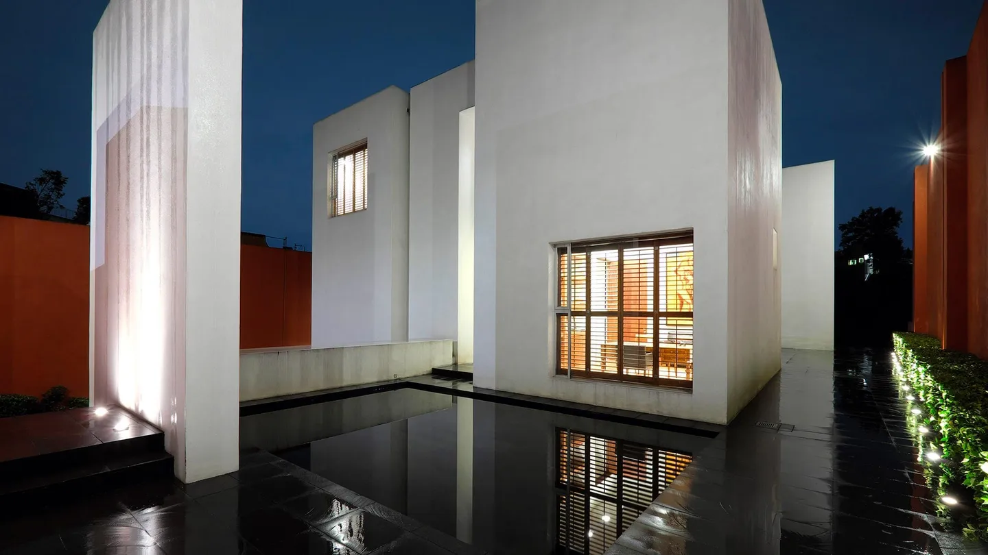 Casa TE: volúmenes blancos y espejo de agua iluminados de noche