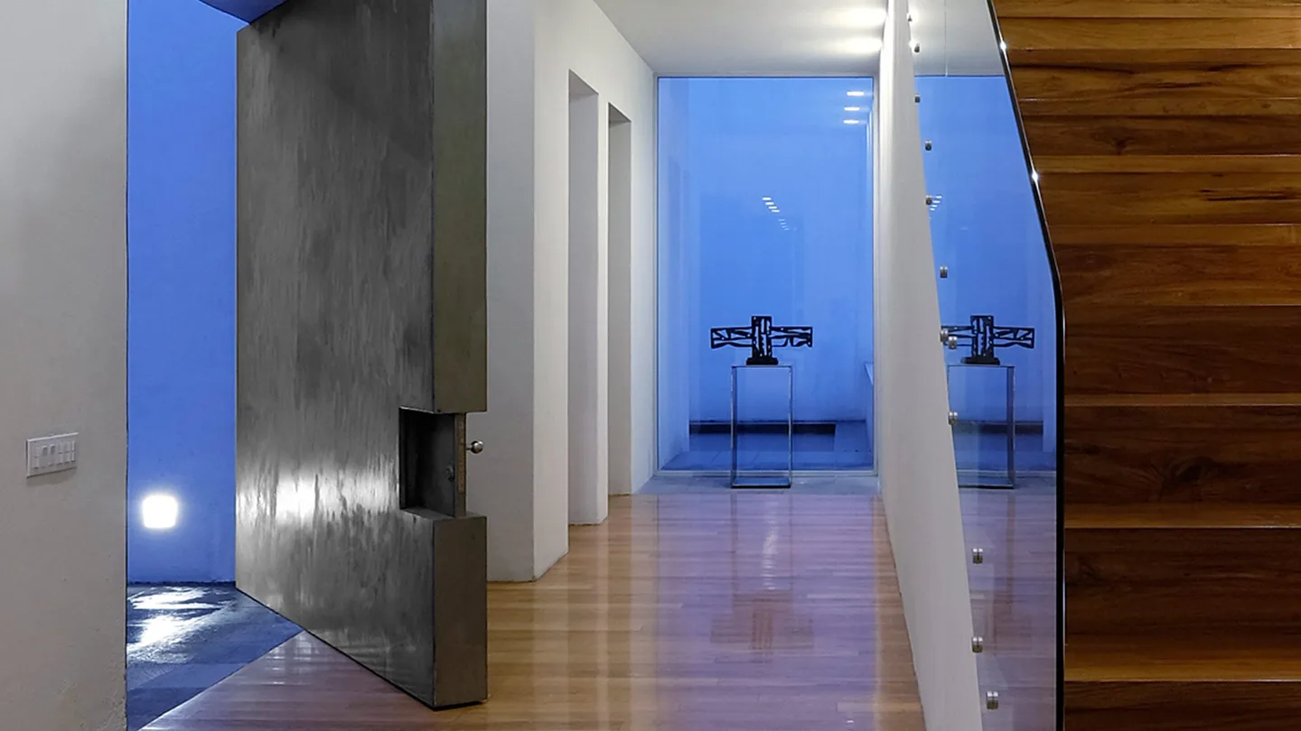 Casa TE: vestíbulo con muro de concreto y vista al patio en la hora azul