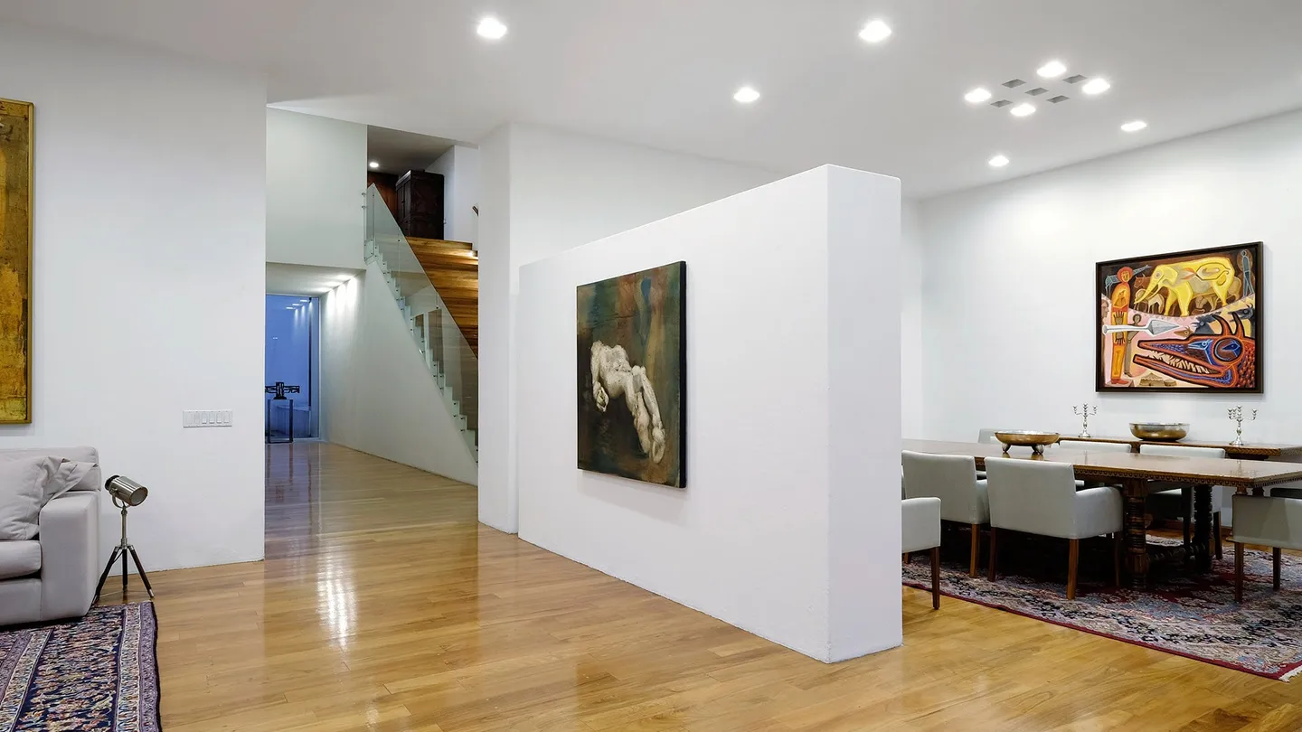 Casa TE: comedor y estancia de muros blancos con pinturas