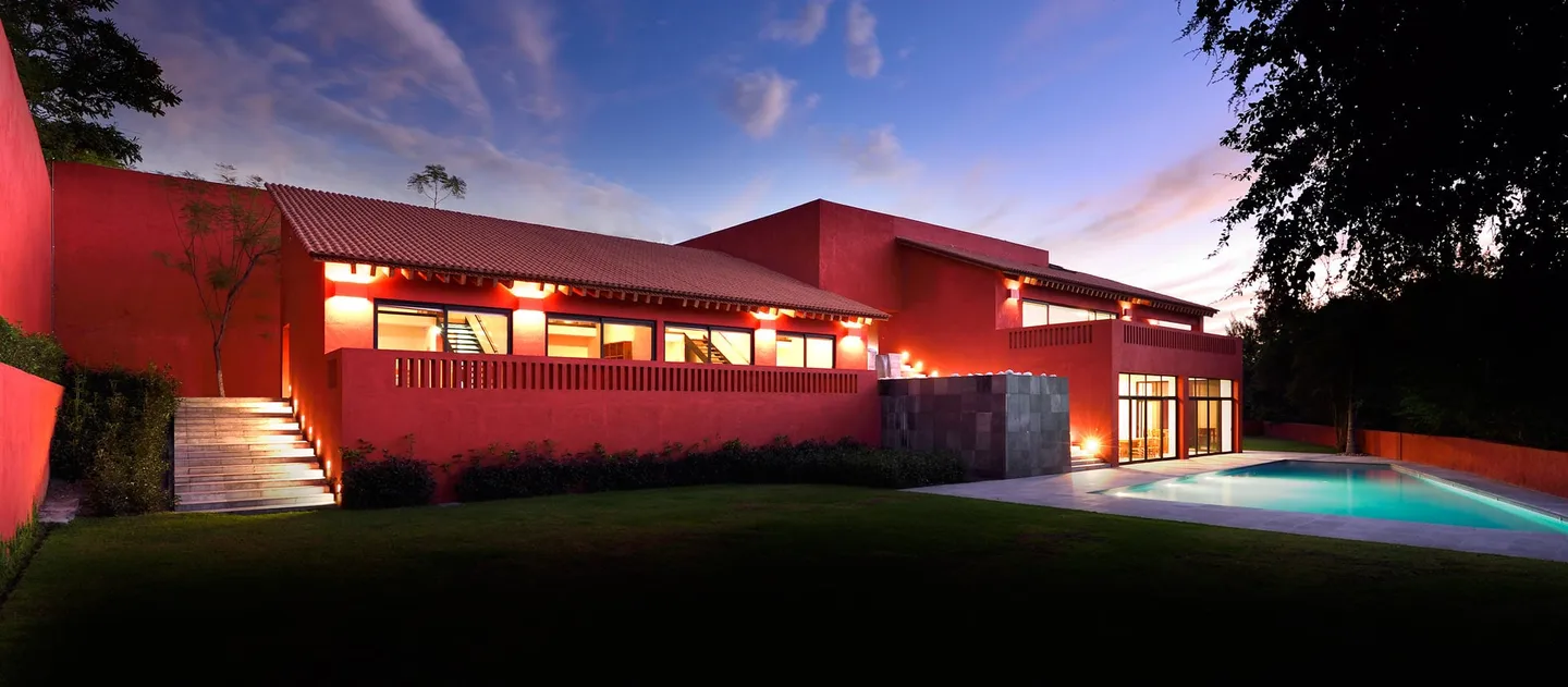 Casa CU 2: muros rojos y alberca frente al jardín, al atardecer