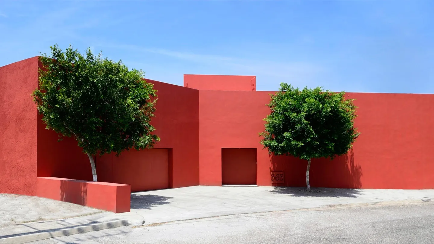Casa CU 2: fachada roja a la calle con dos árboles