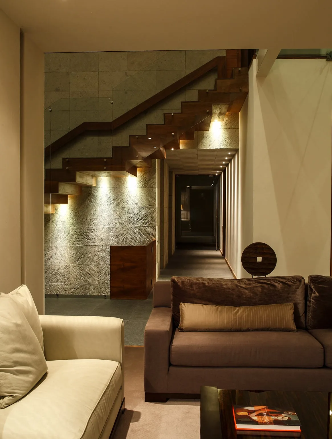 Casa CU: escalera flotante iluminada al fondo de la estancia
