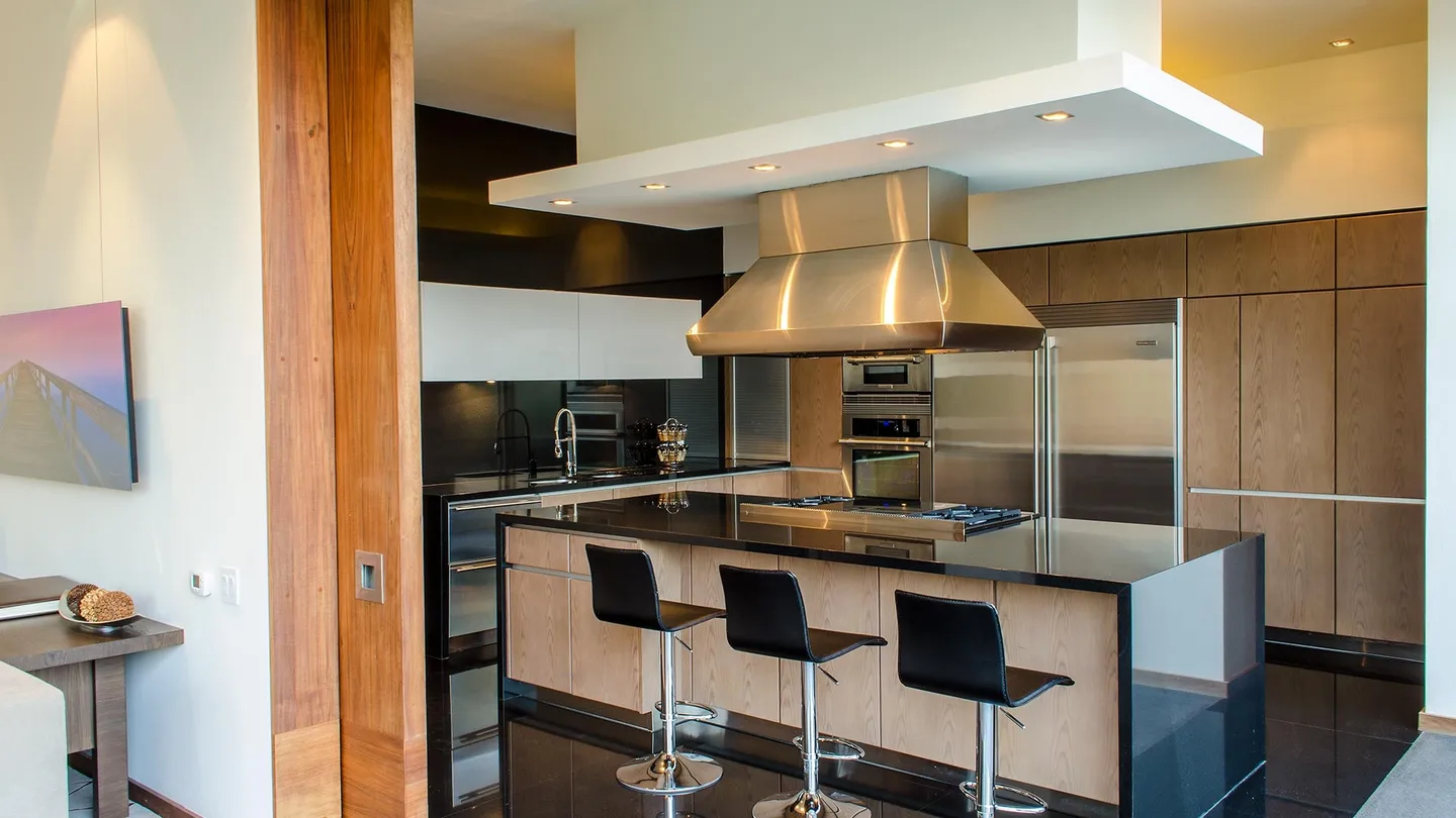 Casa CU: cocina con isla de cubierta oscura y campana de acero
