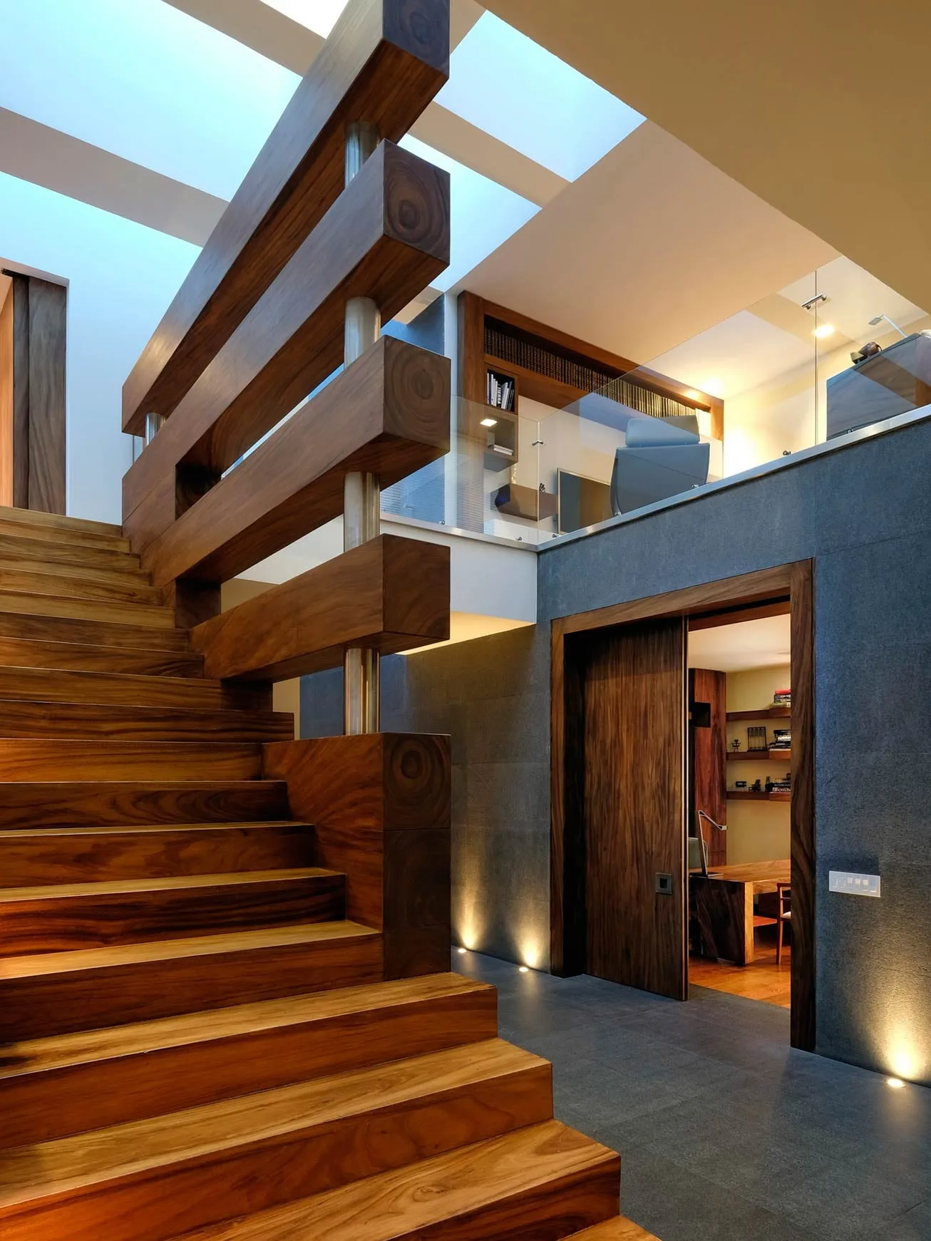 Casa FU3: escalera de madera junto al acceso iluminado