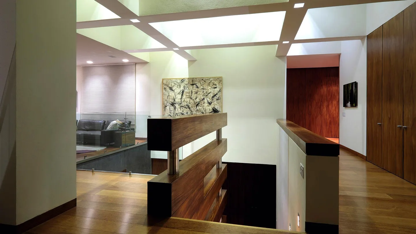 Casa FU3: pasillo de madera en la planta alta bajo un tragaluz