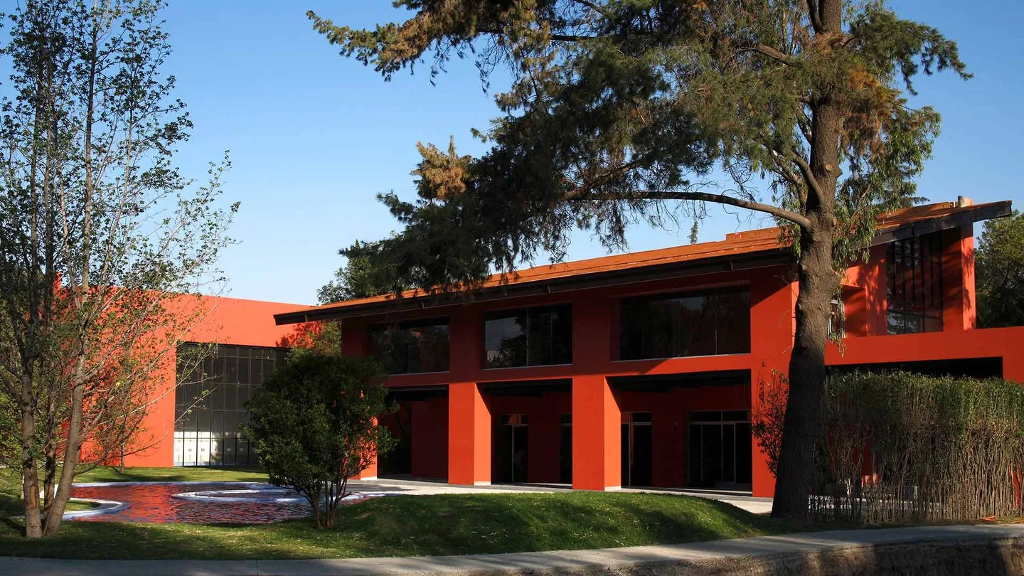 Hacienda San Miguel: edificio de muros rojos entre árboles maduros