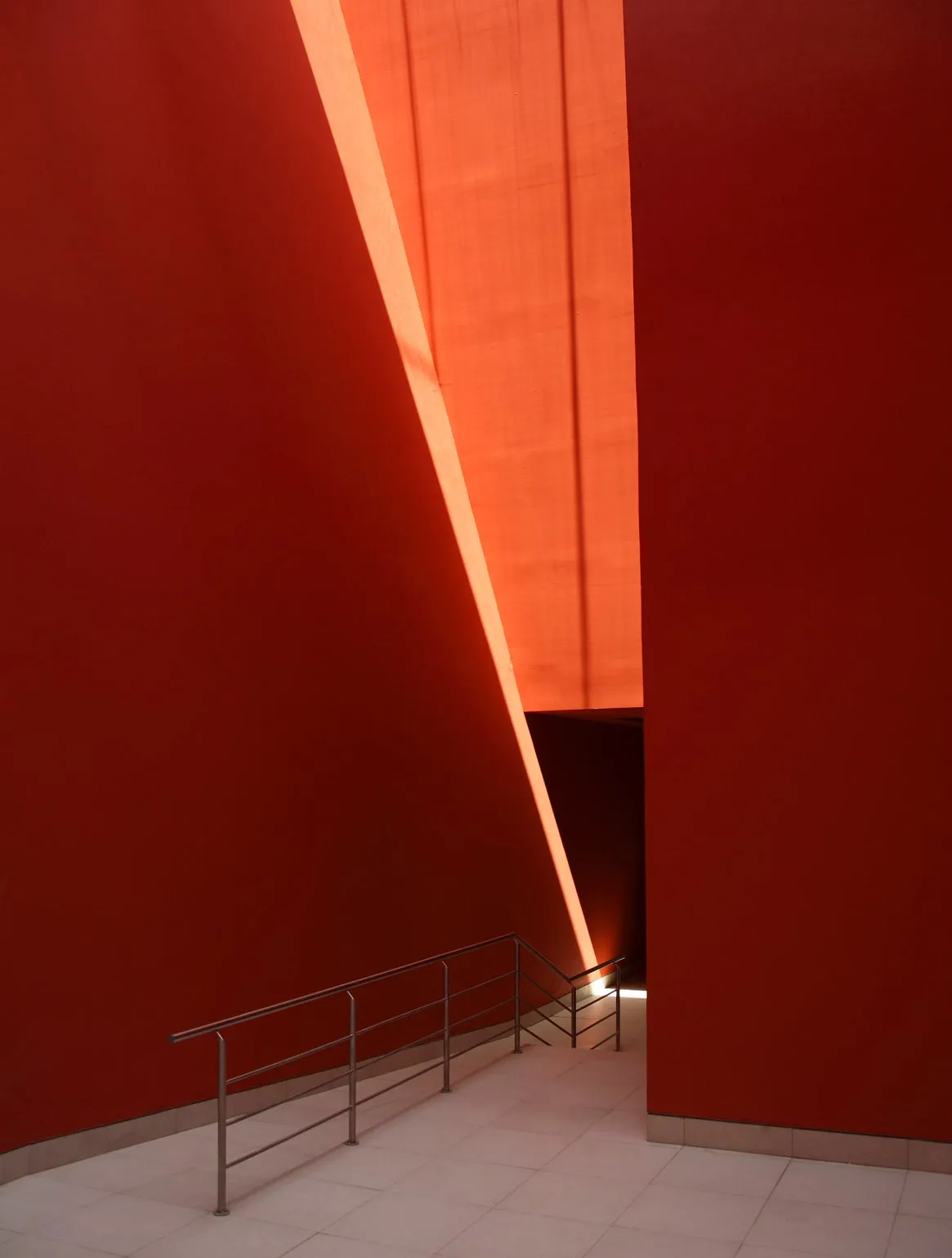 Hacienda San Miguel: rampa entre muros rojos con una franja de luz