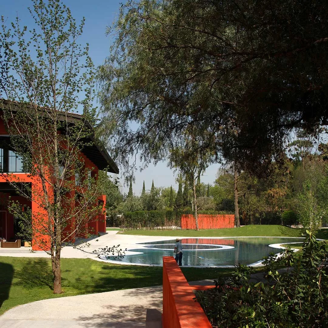 Hacienda San Miguel: jardín con estanque y muros rojos bajo los árboles