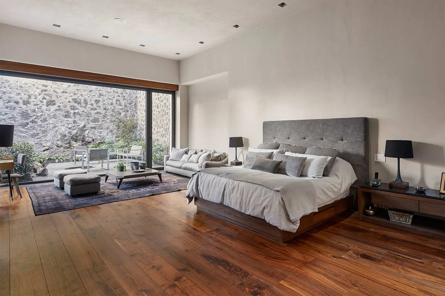 Casa IG: recámara con piso de madera abierta a un patio de piedra