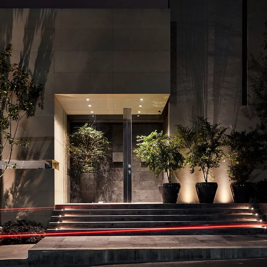 Casa LA: acceso de noche con escalones iluminados y macetas