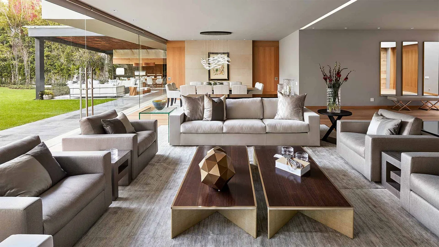 Casa LA: estancia abierta al jardín con mesas de centro de madera