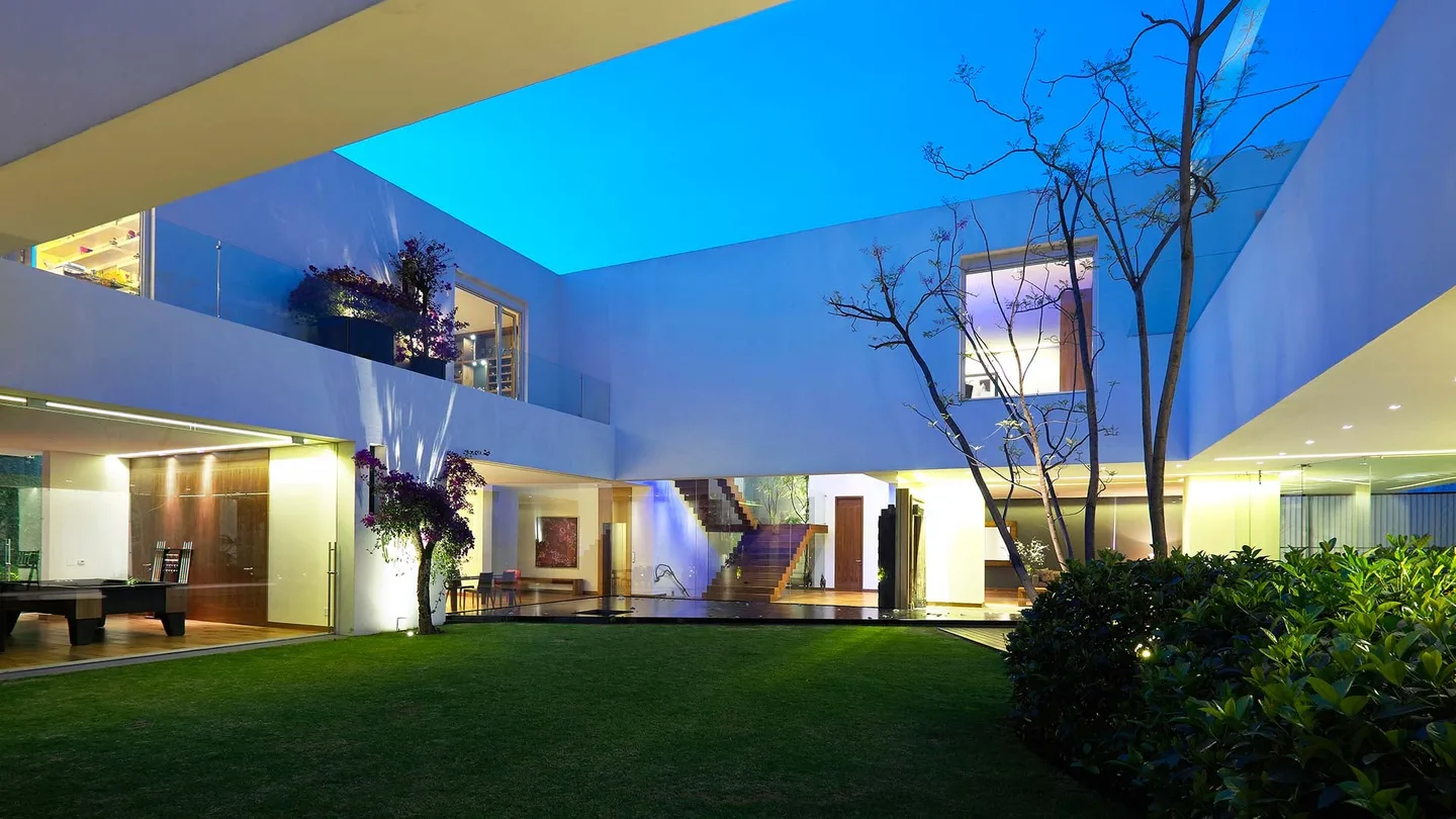 Casa LV: patio rodeado por la casa en la hora azul