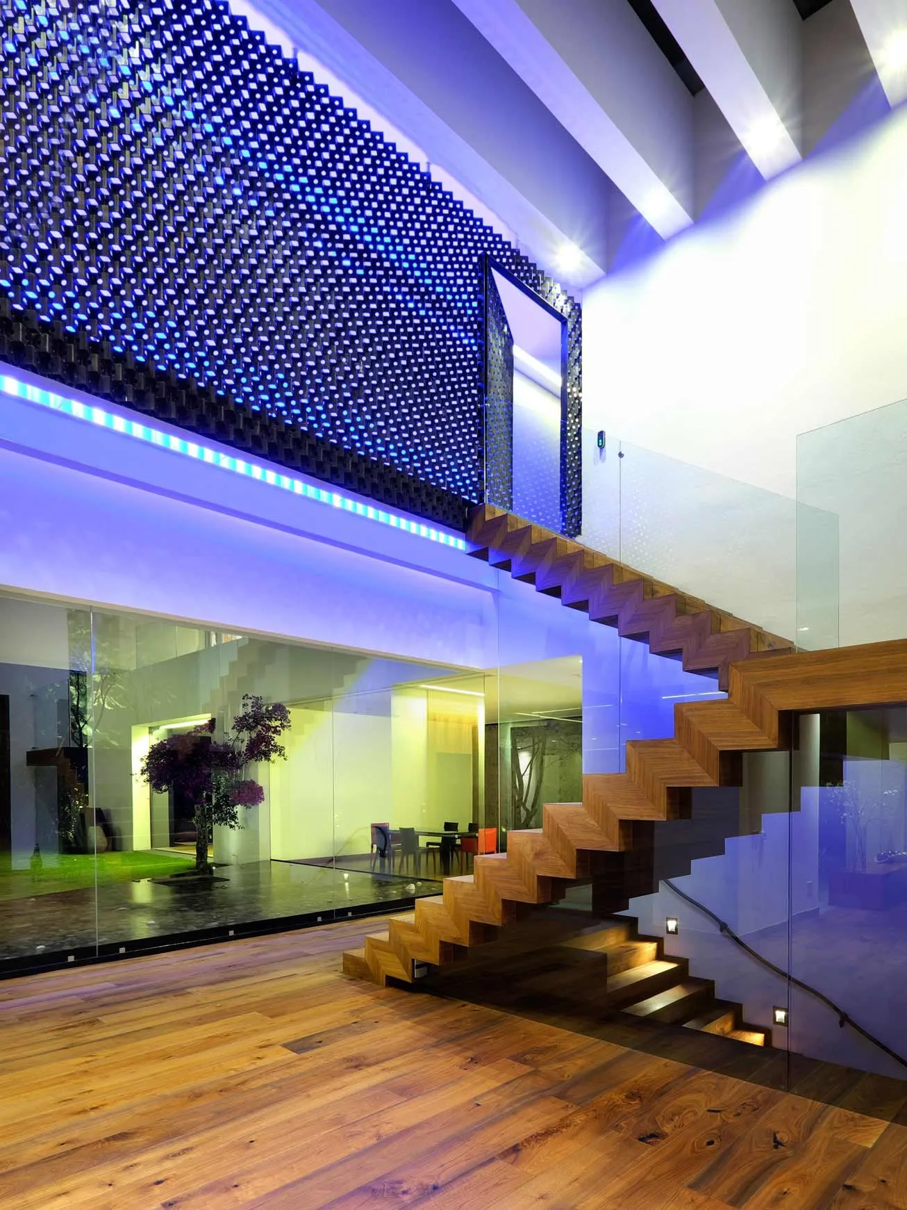 Casa LV: escalera de madera bajo una celosía iluminada en azul