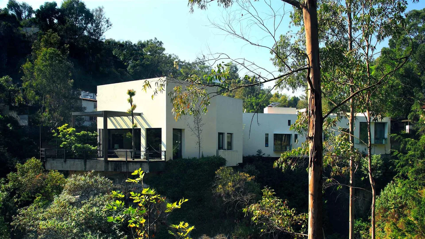 Casa LO: volúmenes blancos asomados entre el bosque