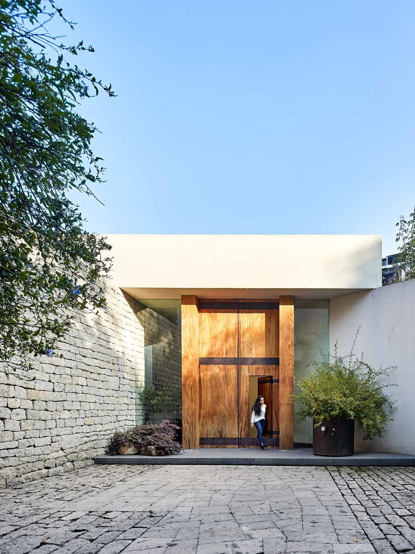Casa LO: acceso con puerta de madera entre muros de piedra