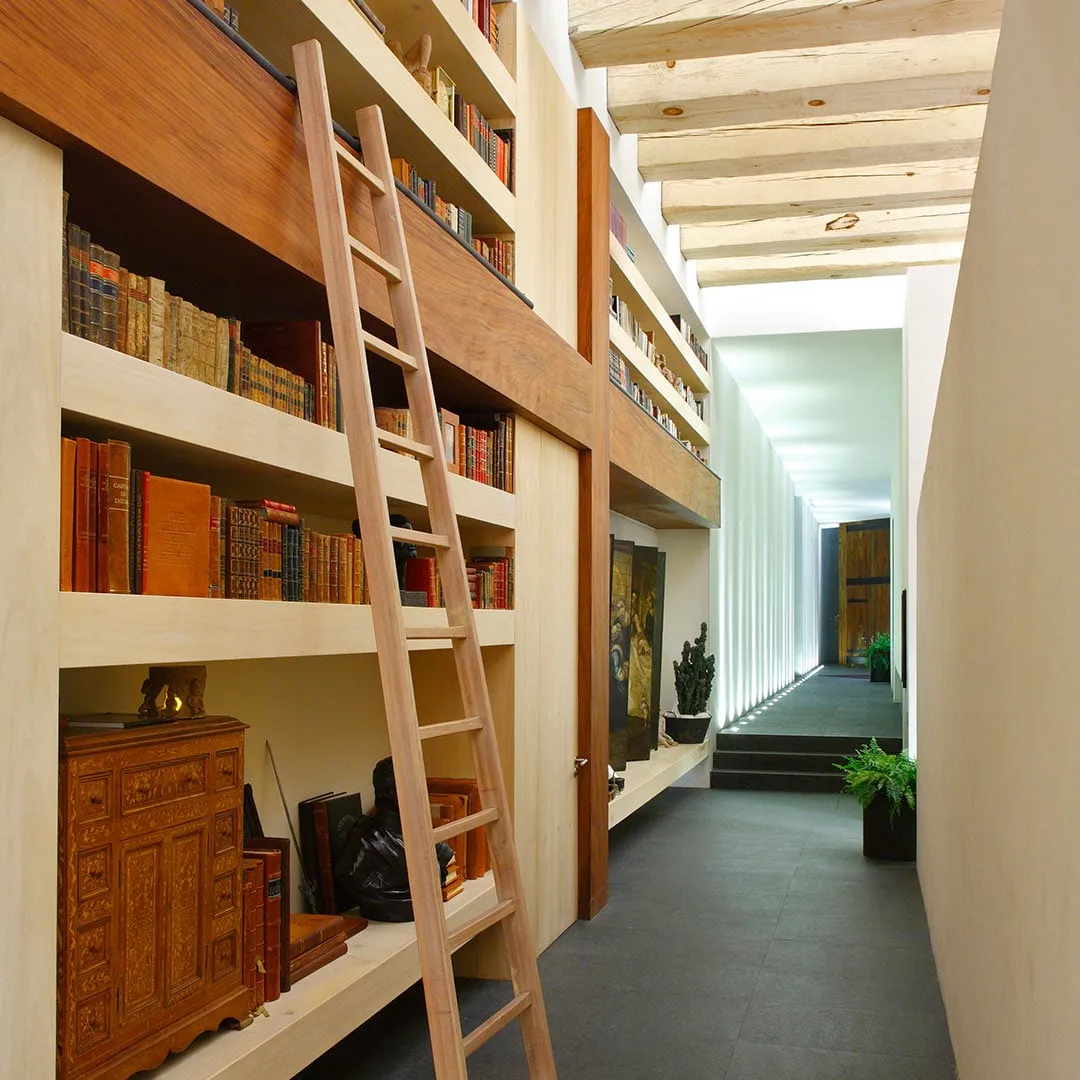 Casa LO: biblioteca con escalera de madera a lo largo de un pasillo