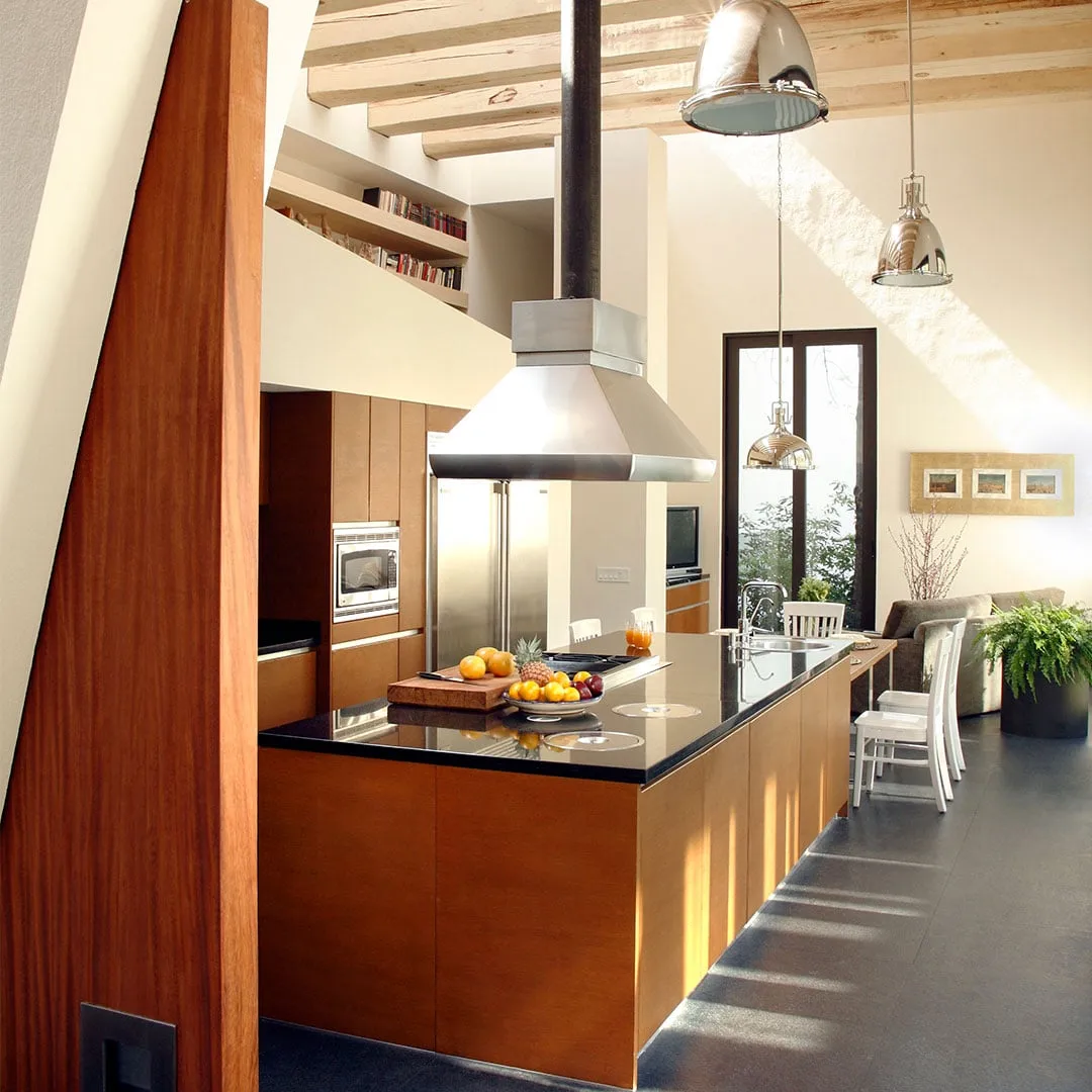 Casa LO: cocina con isla de madera bajo una campana de acero