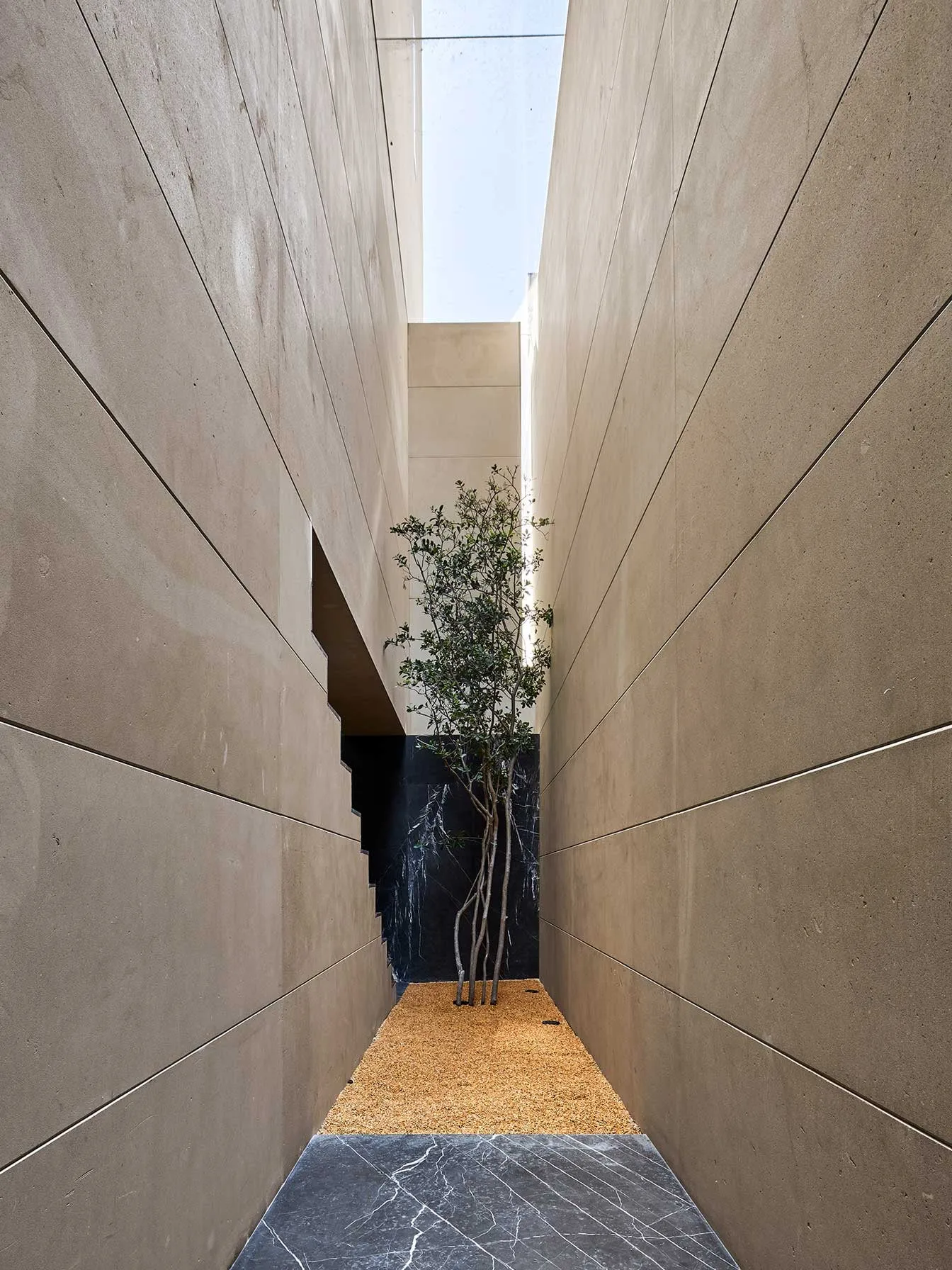 Casa NS: patio estrecho entre muros de piedra clara
