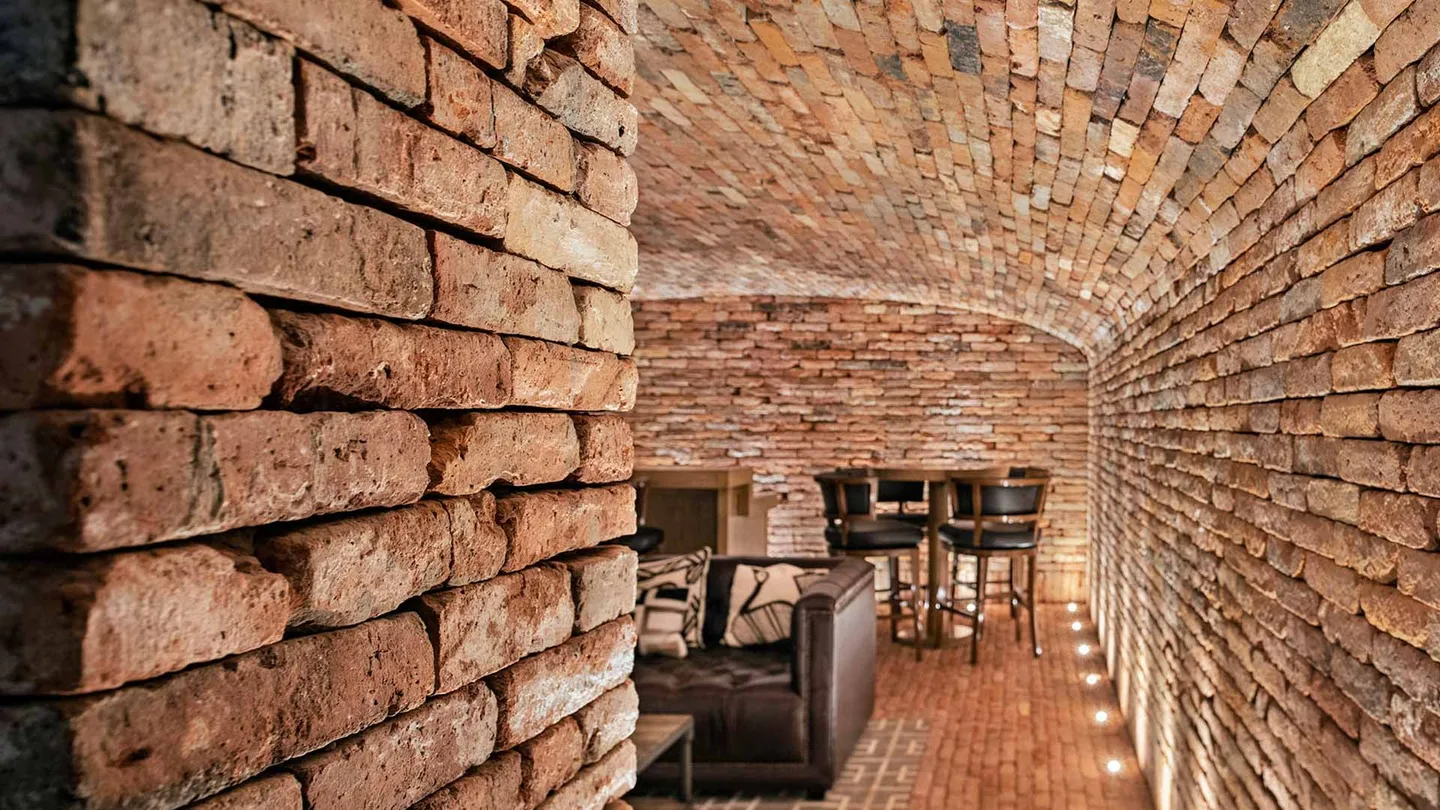 Casa OC: muro de ladrillo y bóveda iluminados desde el piso