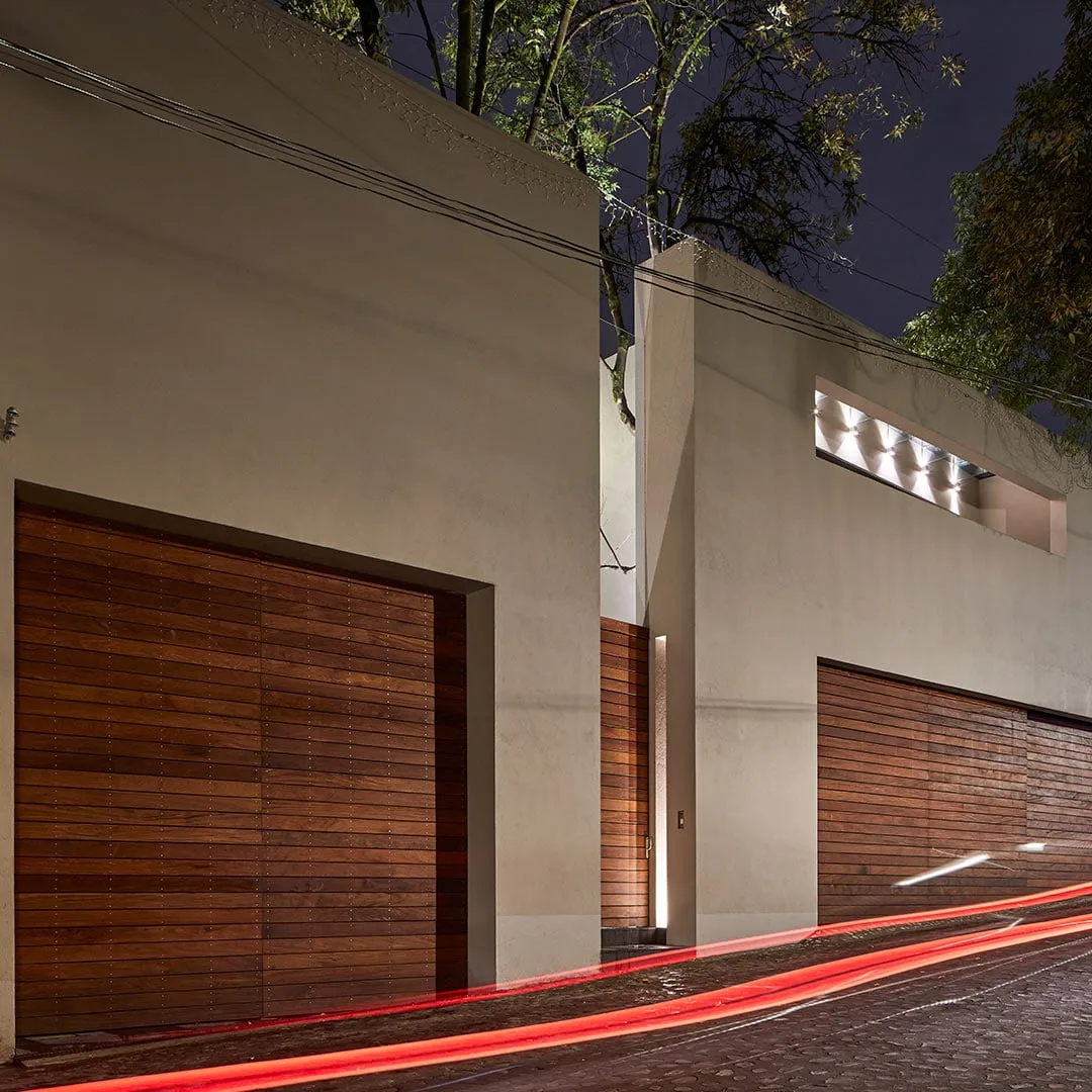 Casa PD: muros de madera y concreto en el acceso, de noche