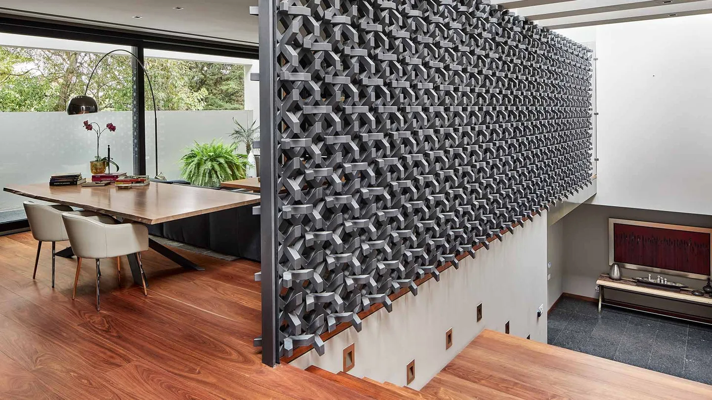 Casa PD: comedor junto a una celosía de piezas oscuras