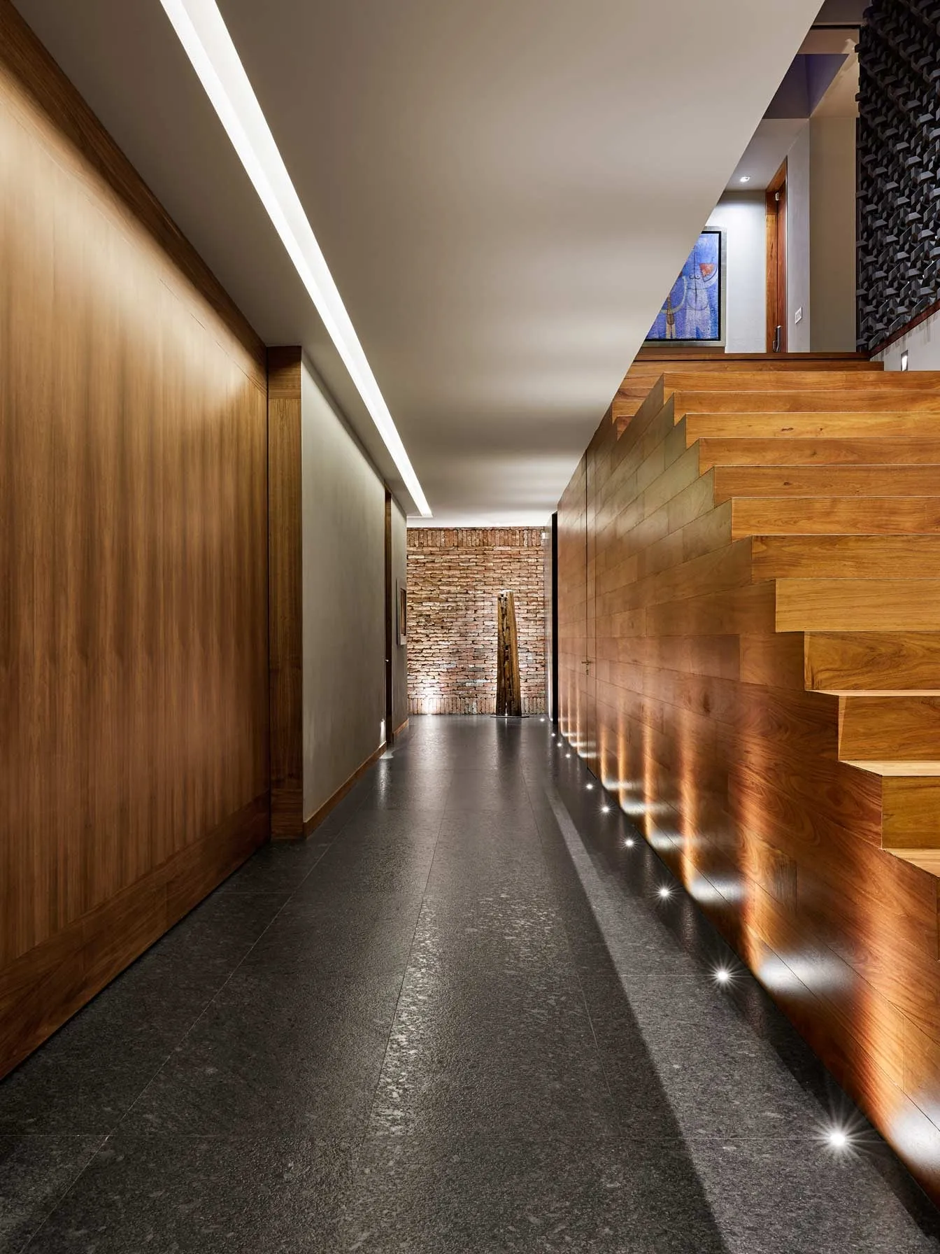 Casa PD: pasillo de madera junto a la escalera, con luz rasante