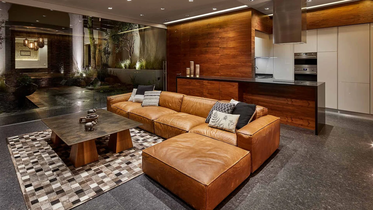Casa PD: estancia y cocina con muro de madera y piso de granito