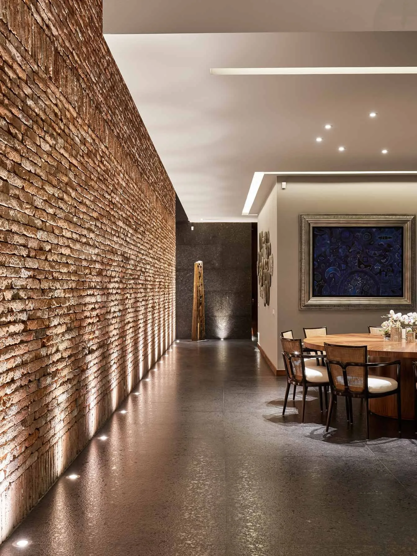 Casa PD: muro de ladrillo iluminado a lo largo del comedor