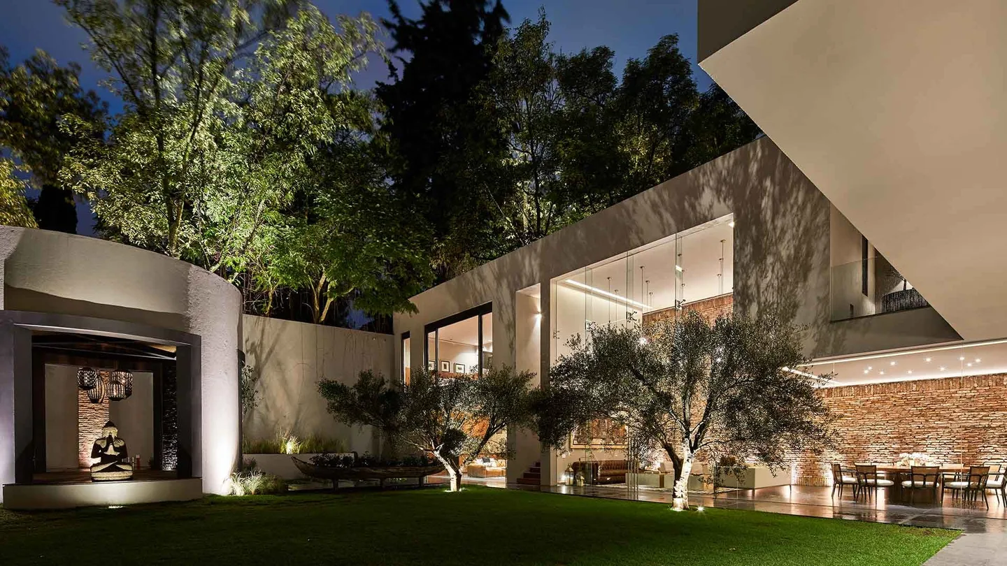 Casa PD: jardín con olivos frente a la casa iluminada