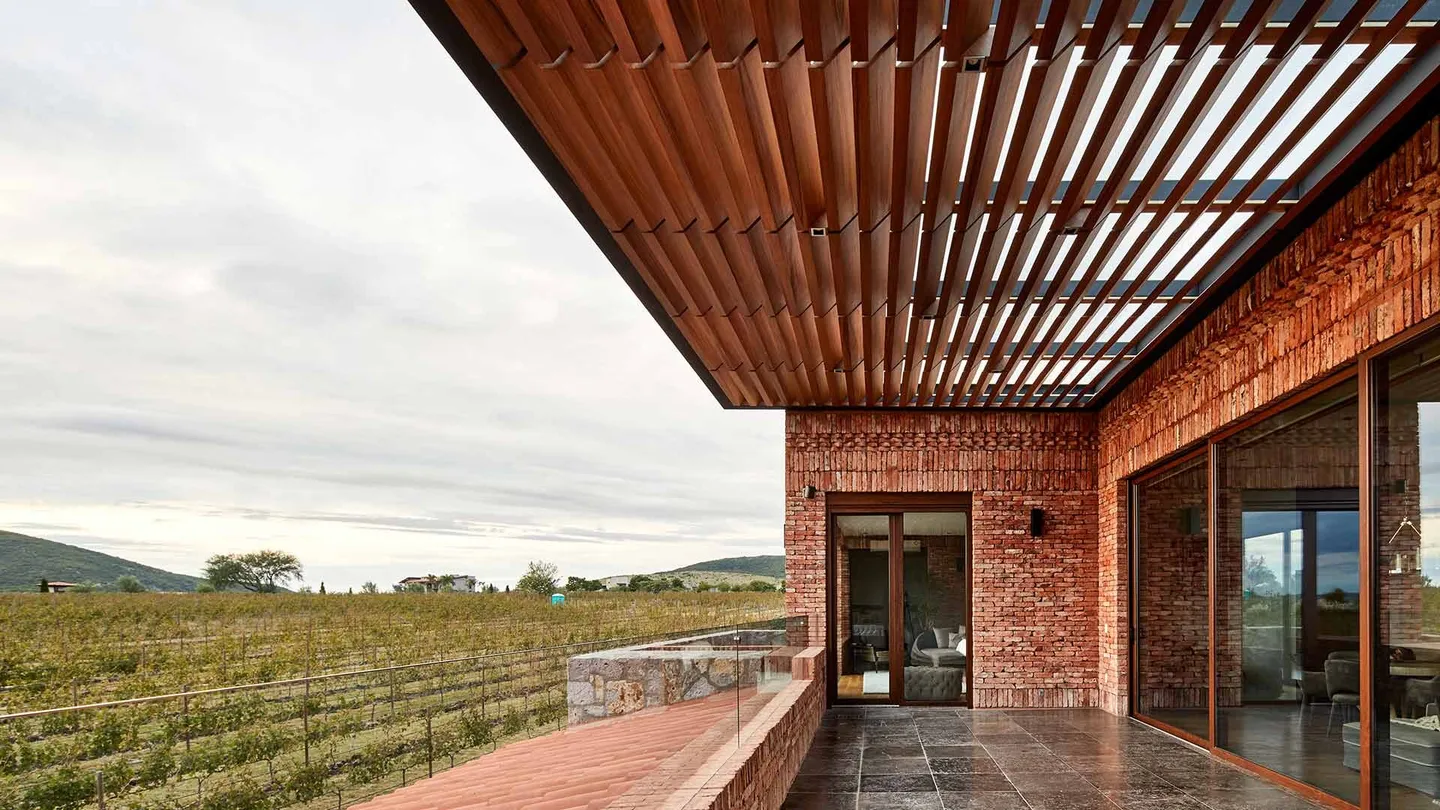Casa SM: terraza con pérgola de madera frente a los campos