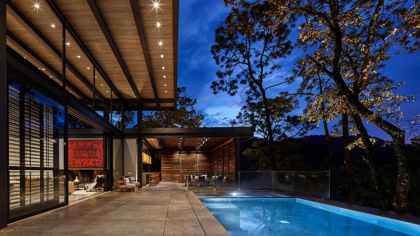 Casa VB: alberca y terraza bajo la cubierta, en la hora azul