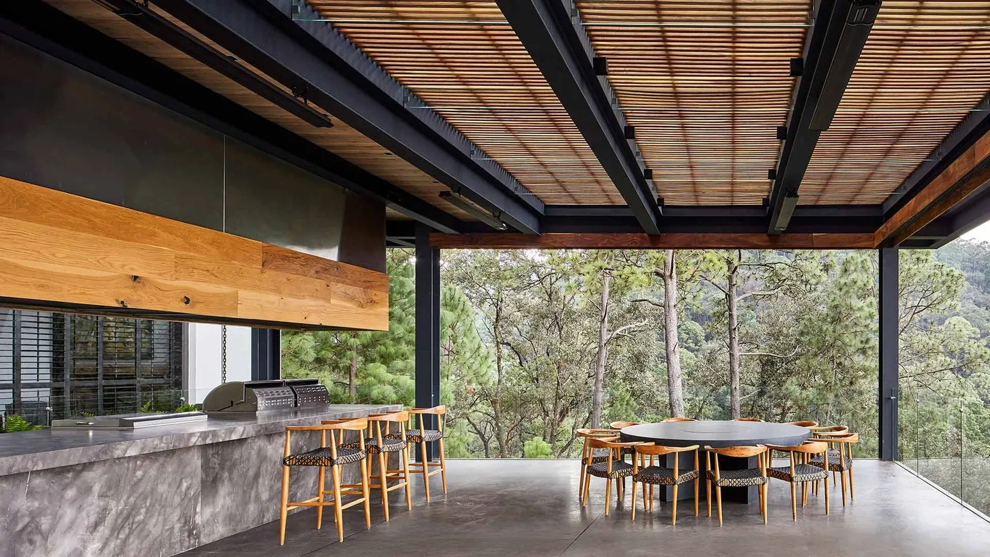 Casa VB: comedor y cocina exteriores bajo una celosía de madera