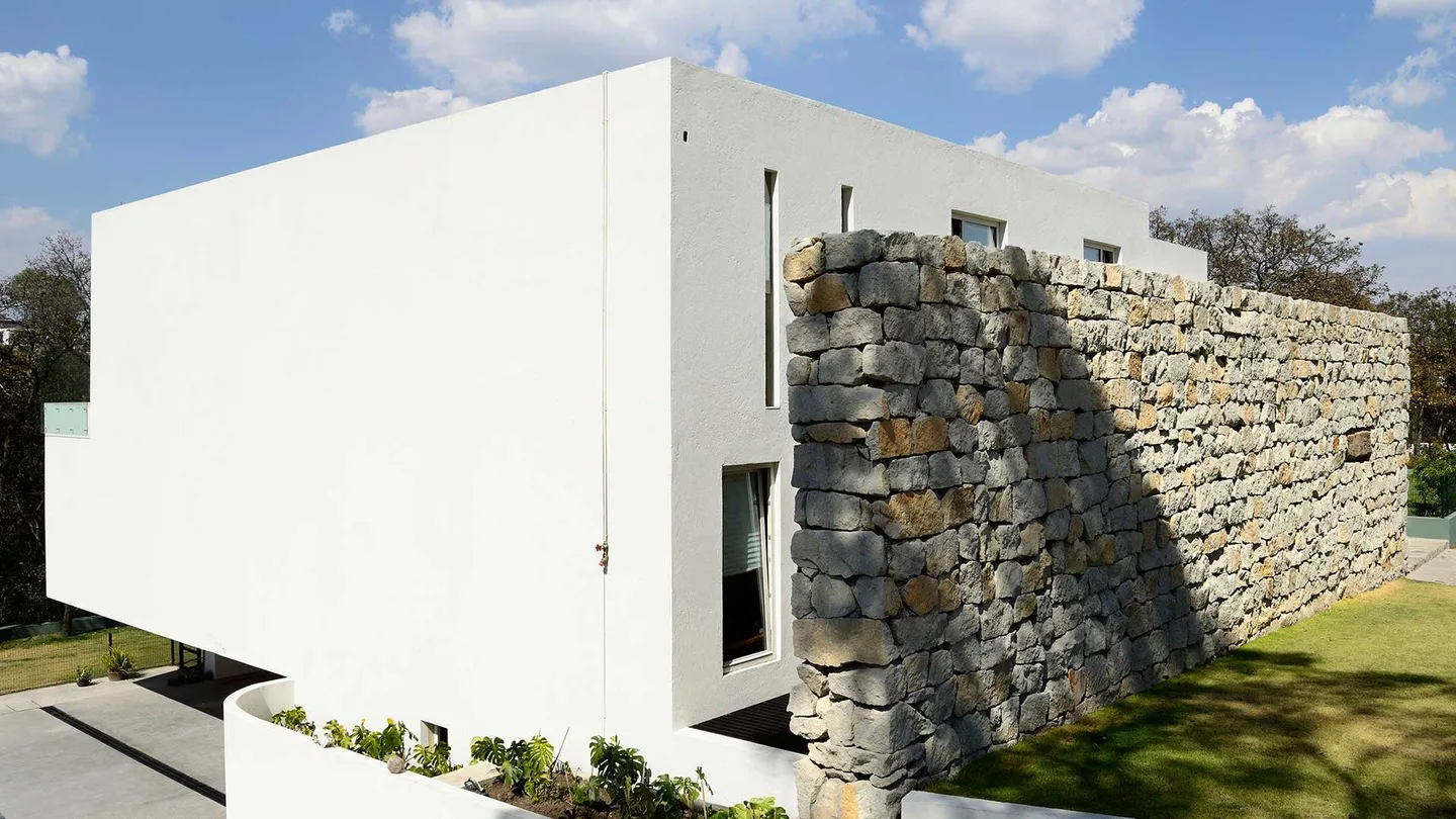 Casa VE: muro de piedra apilada junto al volumen blanco