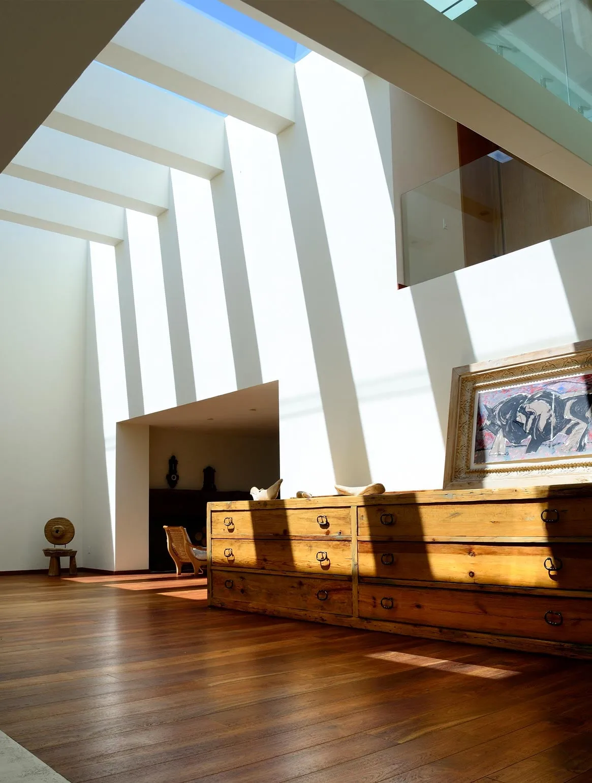 Casa VE: estancia con franjas de luz cenital sobre el piso de madera