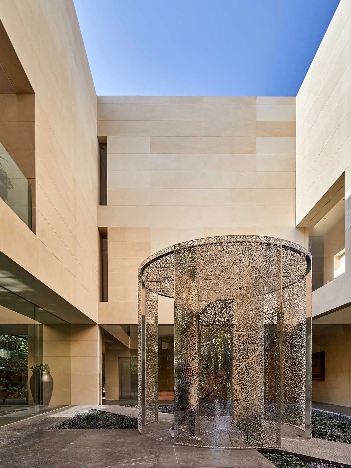 Casa LU: patio con la escalera dentro de un cilindro de vidrio